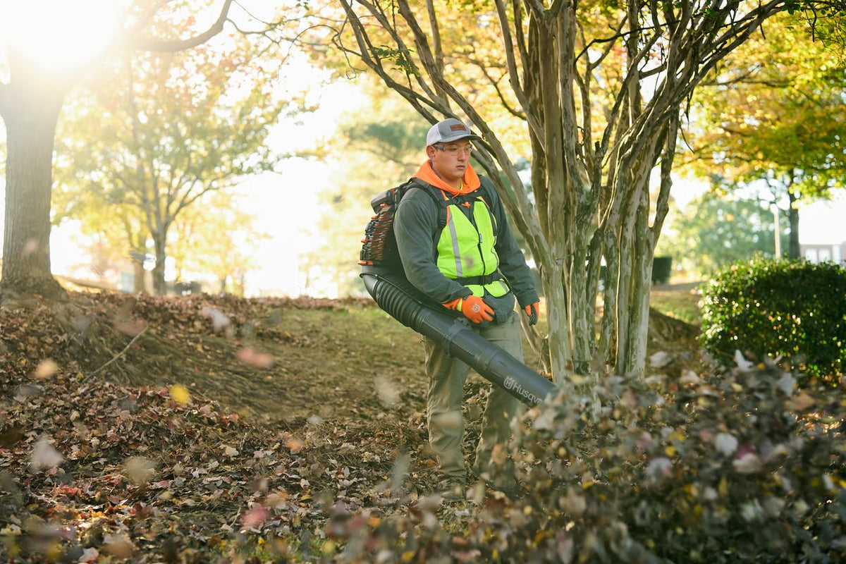 Husqvarna 590BTS backpack blower clearing leaves in a park